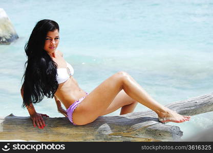 Woman sitting on tree near sea