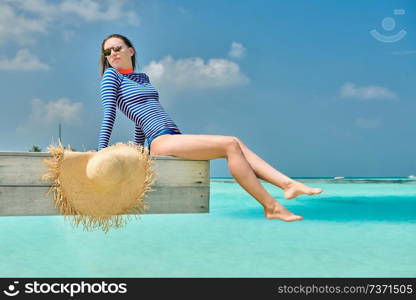 Woman sitting on wooden beach jetty. Summer vacation at Maldives.