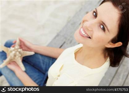 Woman sitting outdoors holding starfish