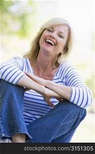 Woman sitting outdoors laughing