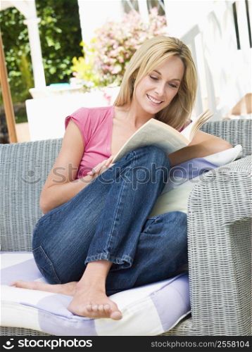Woman sitting outdoors on patio with book smiling