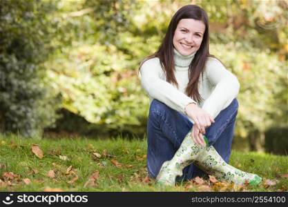 Woman sitting outdoors smiling (selective focus)