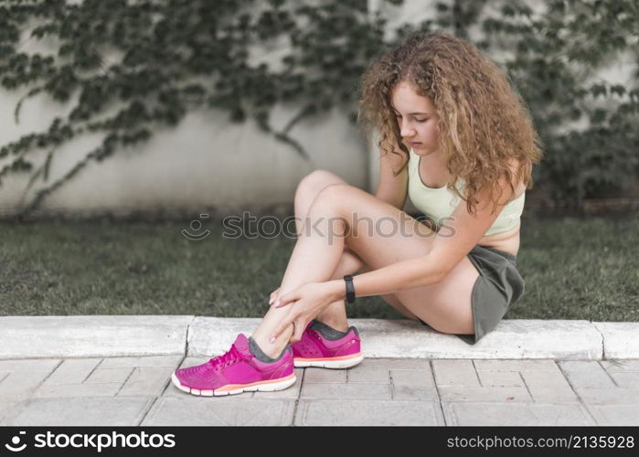 woman sitting park looking injured ankle