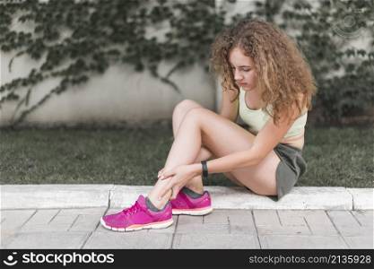 woman sitting park looking injured ankle