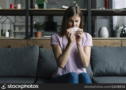 woman sitting sofa blowing nose with tissue paper