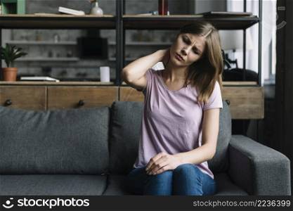 woman sitting sofa suffering from neck pain