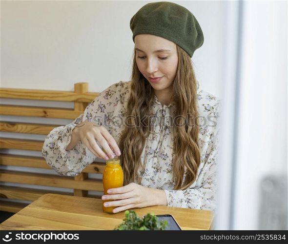 woman sitting table holding fresh juice bottle
