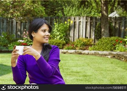 Woman sitting with a cup of tea in a garden
