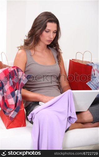 Woman sitting with computers and bags full of clothes