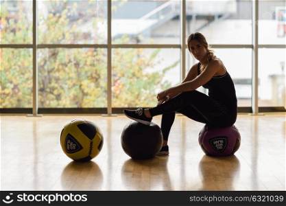 Woman sitting with fitballs in the gym. Young female wearing sportswear clothes.