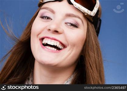 Woman skier girl wearing ski googles portrait. Winter sport activity. Beautiful happy smiling sportswoman on blue studio shot. skier girl wearing warm clothes ski googles portrait.