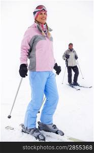 Woman skier standing on ski slope man on skis in background