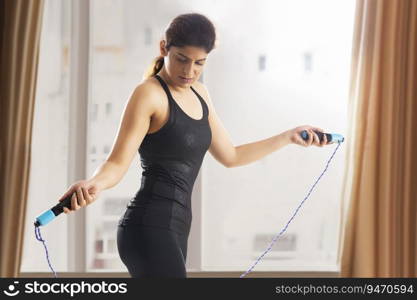 Woman skipping with a skipping rope inside her home. 