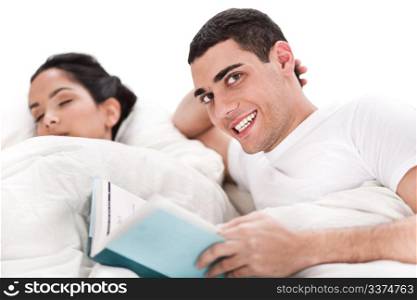 Woman sleeping and man happily reading book in bed over white background