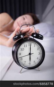 woman sleeping and wake up to turn off the alarm clock in the morning