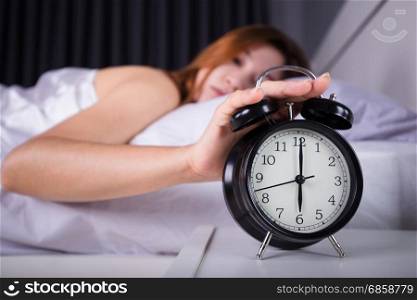 woman sleeping and wake up to turn off the alarm clock in the morning
