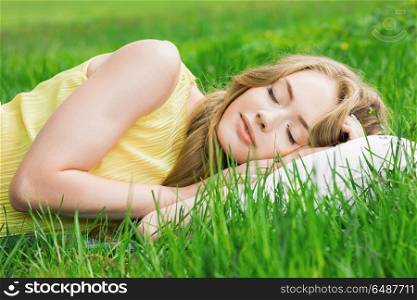 Woman sleeping on grass. Young woman sleeping on soft pillow in fresh spring grass