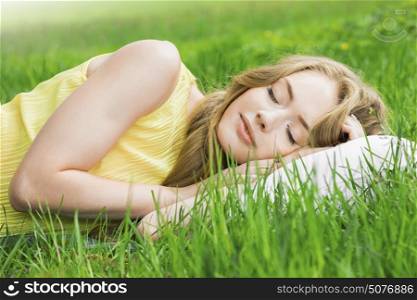 Woman sleeping on grass. Young woman sleeping on white pillow in fresh spring grass