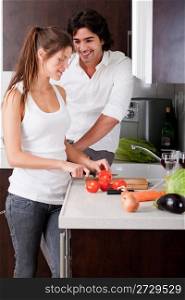 woman sliceing tomatoes with her boyfriend in kitchen