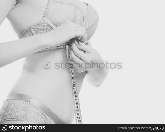 Woman slim girl in bra lingerie with measure tape measuring her chest breasts. Closeup part of female body. Black & white. Woman in bra lingerie measuring her chest breasts.