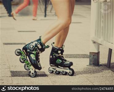 Woman slim legs wearing roller skates standing outside. Sport activity objects concept.. Woman legs wearing roller skates