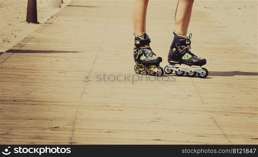Woman slim legs wearing roller skates standing outside. Sport activity objects concept.. Woman legs wearing roller skates