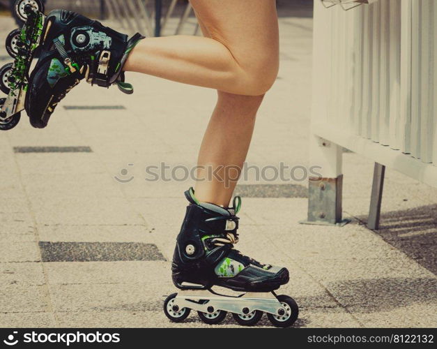 Woman slim legs wearing roller skates standing outside. Sport activity objects concept.. Woman legs wearing roller skates