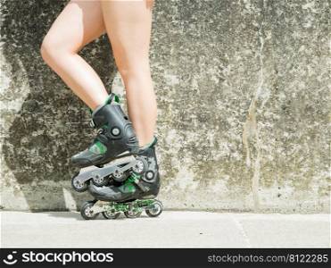 Woman slim legs wearing roller skates standing outside. Sport activity, workout and exercising concept.. woman wearing roller skates