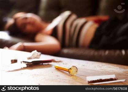 Woman Slumped On Sofa With Drug Paraphernalia In Foreground