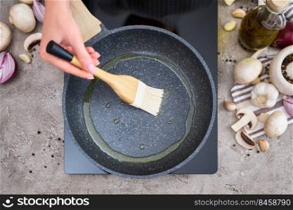 Woman smear olive oil on frying pan with silicone brush at domestic kitchen.. Woman smear olive oil on frying pan with silicone brush at domestic kitchen
