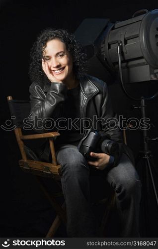 Woman smiling and holding camera in studio setting.