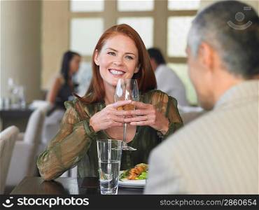 Woman smiling at man over meal in restaurant