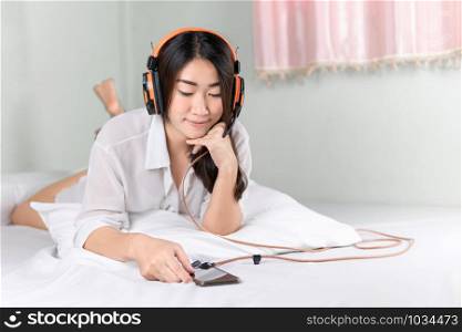 Woman smiling.Beautiful Asian women wearing white shirts listening to happy music in the morning room.