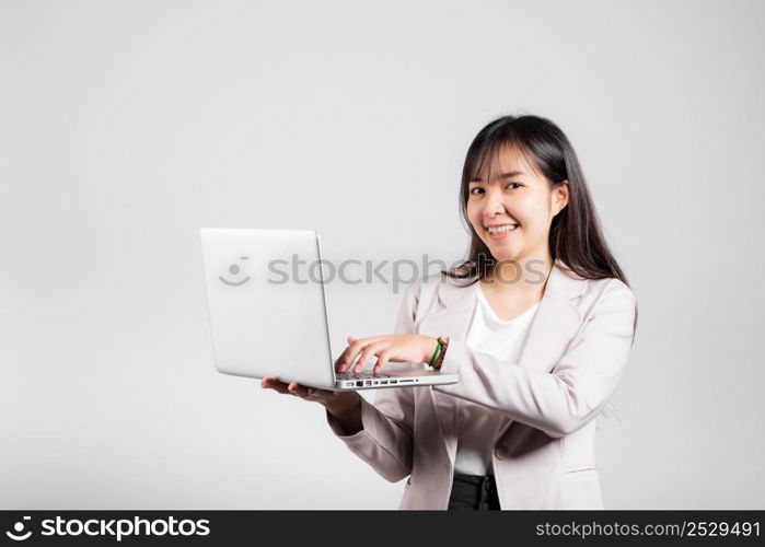 Woman smiling confident smiling holding using laptop computer and typing keyboard for online sending email or chat, Portrait excited happy Asian young female studio shot isolated on white background