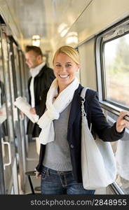Woman smiling in train hall with luggage commuting passenger troller