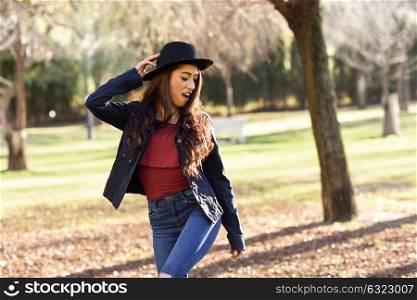 Woman smiling in urban park. Girl wearing casual clothes and hat.