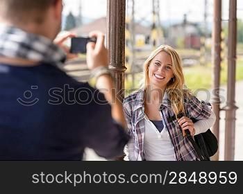 Woman smiling man taking her picture vacation backpack railroad camera