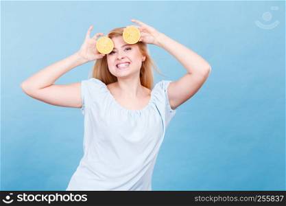 Woman smiling teen girl holding two halfs of yellow lemon citrus fruit in hands, on blue. Healthy diet nutrition.. Girl holding lemon citrus fruit