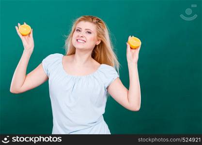 Woman smiling teen girl holding two halfs of yellow lemon citrus fruit in hands, on dark green. Healthy diet nutrition.. Girl holding lemon citrus fruit