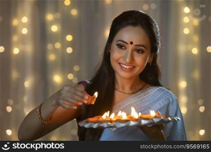 Woman smiling while keeping a diya in the plate