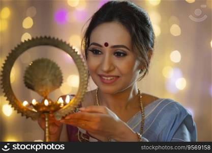Woman smiling while lighting a l&with diya