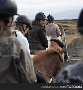 Woman smiling while riding Icelandic horses in a row