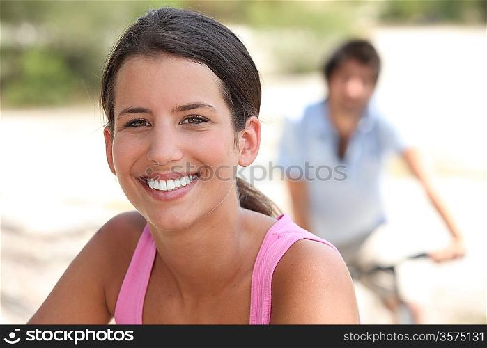 woman smiling with a man biking in background