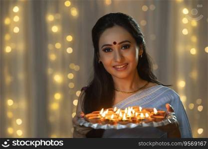 Woman smiling with a plate of diyas in her hand