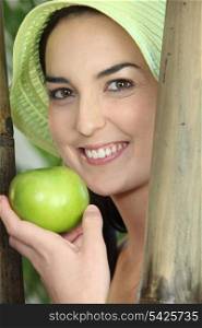 Woman smiling with green hat and apple