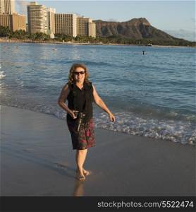 Woman smiling with holding a camera on the beach, Waikiki, Honolulu, Oahu, Hawaii, USA