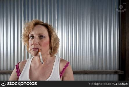 Woman smoking cigarette in front of corrugated metal