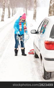 Woman snow standing with car tire chains holding winter broken