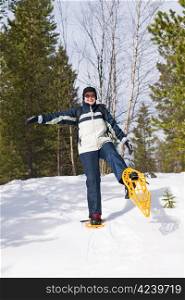 Woman snowshoeing in the forest and smiling.