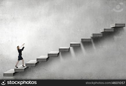 Woman speaking in horn. Young businesswoman on staircase proclaiming something in horn